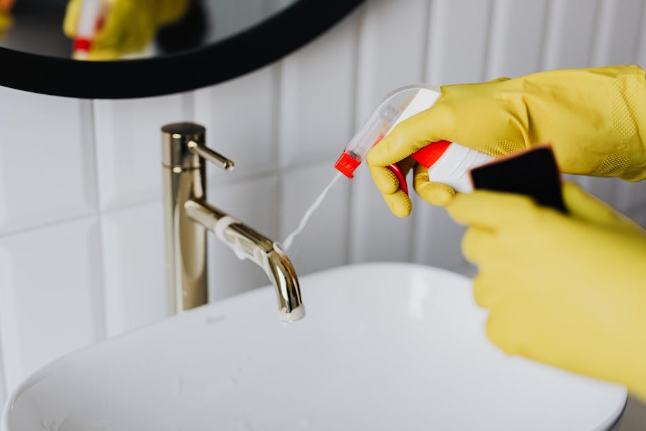 Two professional cleaners from Acton Carpet Cleaners are performing surface cleaning and sanitation on a busy city street at Churchfield Road in Acton. They are wearing high-visibility orange and red 