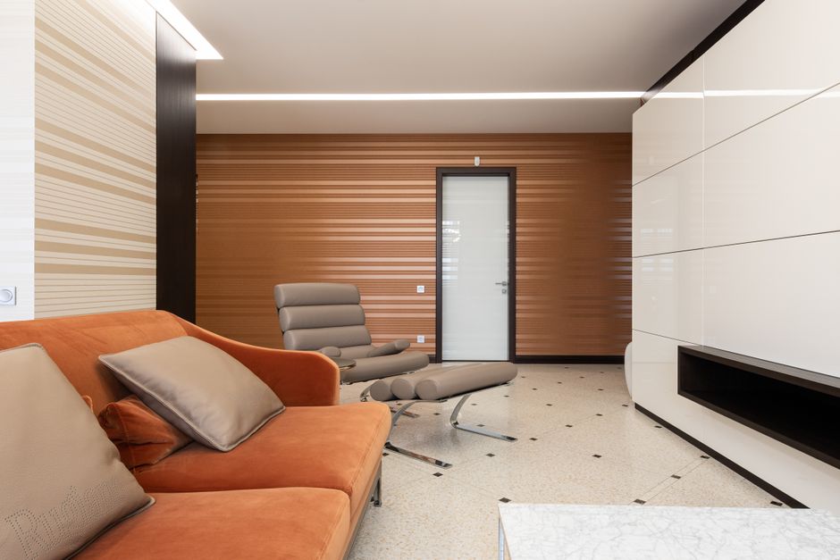 Close-up view of a grey upholstered sofa with matching cushions, situated in a well-lit living room. The fabric appears clean and free of dust, with smooth, neat seams and a subtle texture. The surrou